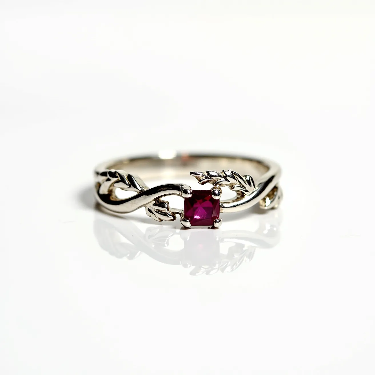 This unique wedding ring features a delicate and intricate band crafted from shiny metal, likely white gold or platinum, with a charming leaf motif that wraps gracefully around the finger. At its center, a bright, square-cut ruby is set in a secure four-prong setting, adding a vibrant pop of color and elegance. The design incorporates a nature-inspired theme with the leaves intertwining seamlessly into the band's structure, creating a harmonious blend of sophistication and natural beauty.