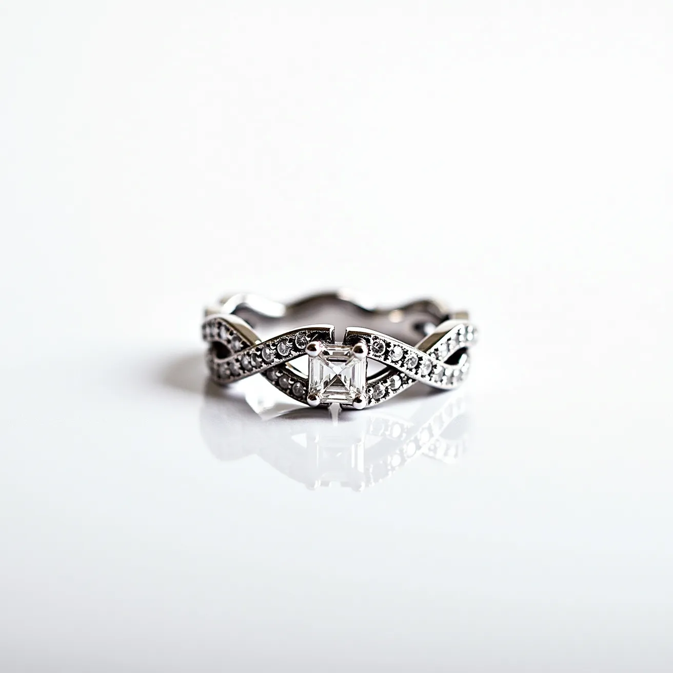 This western wedding ring features an elegant design crafted from what appears to be a lustrous white metal, possibly white gold or platinum, which forms an intricate twist pattern. The centerpiece is a rectangular-cut diamond, securely set in a prong setting that highlights its brilliance. Flanking the central stone, smaller round diamonds are embedded along the twisting band, further enhancing its sparkle and adding depth to the design. The absence of a clasp suggests a traditional, continuous ring band, offering a seamless and timeless aesthetic.