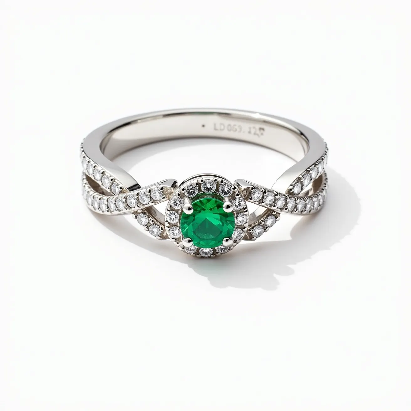 This western wedding ring features a band made of a reflective white metal, likely platinum or white gold. At its center, there is a prominent green gemstone, possibly an emerald, cut in a round shape and held securely in place by a four-prong setting. The band is intricately designed with a crisscross pattern, adorned with small round diamonds that accentuate the central stone. The prong setting not only keeps the gemstone in place but also allows light to enhance its vibrant hue. The diamonds in the band are set in a pave style, adding a continuous sparkling effect to the ring's overall design.