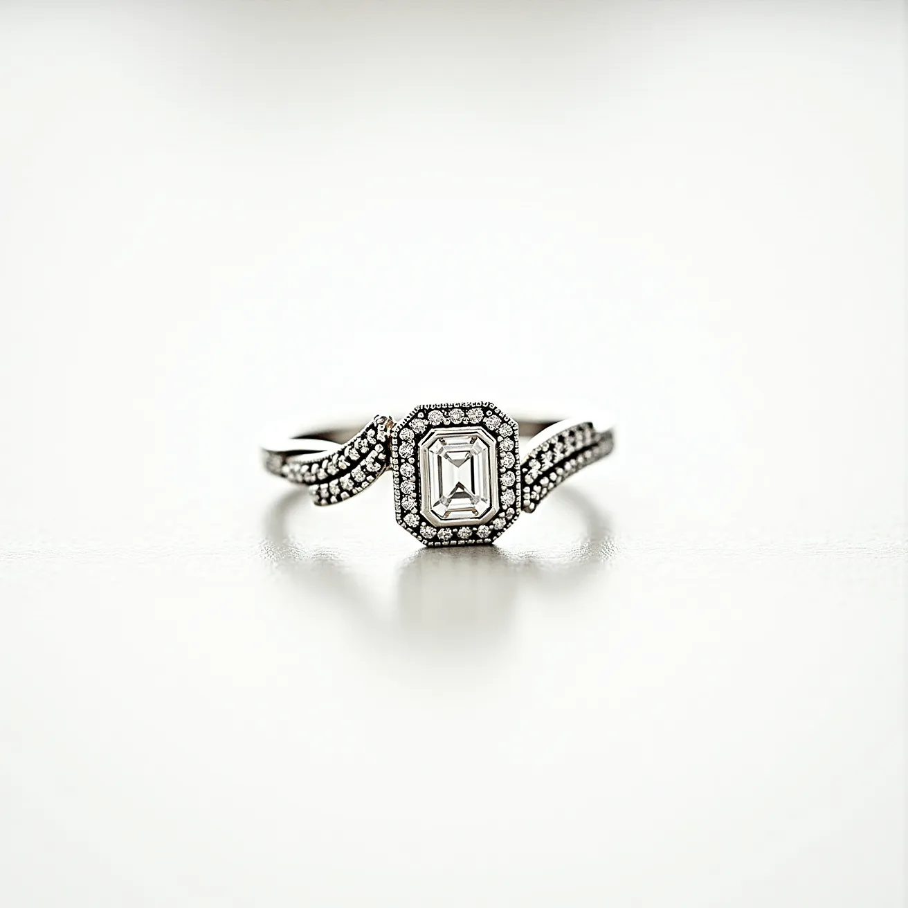 This white gold ring features an elegant design centered around a large emerald-cut diamond, set prominently in the middle. Surrounding this central gem is a halo of smaller round diamonds, enhancing the brilliance and adding to the ring's overall sparkle. The band is crafted from white gold, providing a modern and sophisticated look, and is encrusted with additional small round diamonds along its split shank, further amplifying its luxurious appearance. The setting of the stones appears secure, designed to ensure both durability and visual appeal.