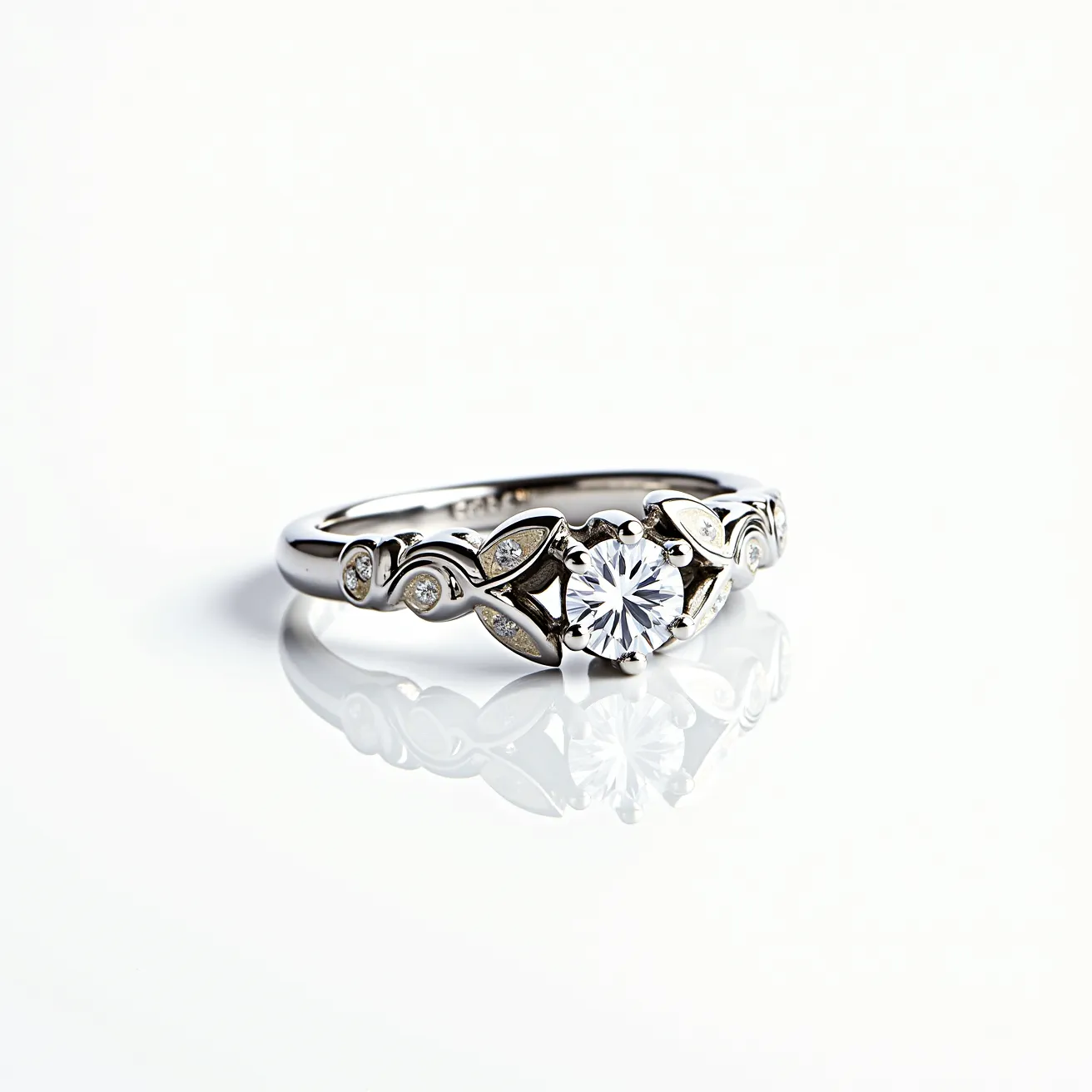 This white gold ring features a central round brilliant-cut diamond, set in a secure prong setting that highlights its brilliance. The band is intricately designed with leaf-like motifs embellished with smaller round diamonds inlaid within the pattern. The combination of the polished white gold and the sparkling diamonds adds elegance and sophistication to the piece. There are no clasps or attachments, as the piece is a traditional ring design.