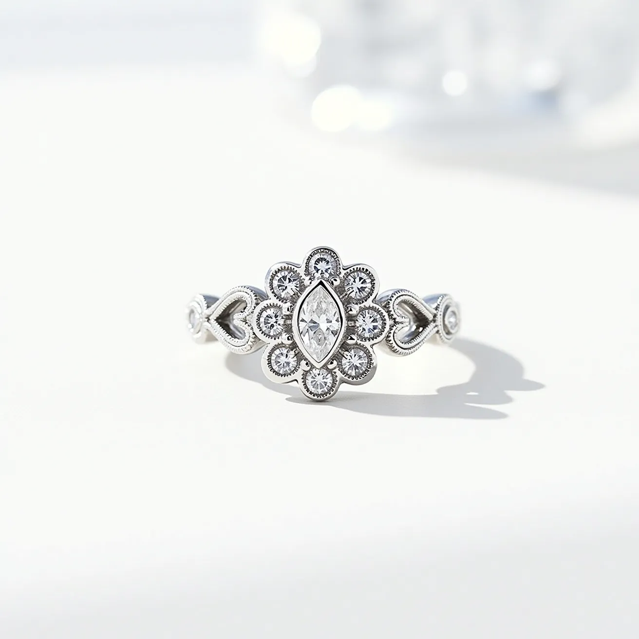 This white gold ring features an intricate design centered around a marquise-cut diamond, elegantly surrounded by smaller round-cut diamonds arranged in a floral pattern. The stones are securely set using a bezel setting, enhancing the overall ornamental design. The band includes heart-shaped details, adding a romantic element to the piece, and the white gold material provides a bright, reflective sheen that complements the brilliance of the diamonds. The overall craftsmanship ensures a seamless integration between the gemstones and the metalwork, resulting in a sophisticated and timeless piece of jewelry.