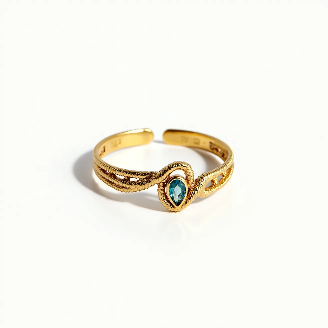 This wrap ring is crafted from a gold-toned metal and features an intricately woven design, forming two parallel bands that elegantly wrap around the finger. At the center of the ring sits a teardrop-shaped blue gemstone, likely a topaz or similar, set into the band with a bezel setting that complements the twisted rope texture surrounding it. The combination of the gemstone's vibrant hue with the lustrous gold finish creates a striking visual contrast. The ring's open design allows for some adjustability, eliminating the need for a clasp or traditional closure mechanism.