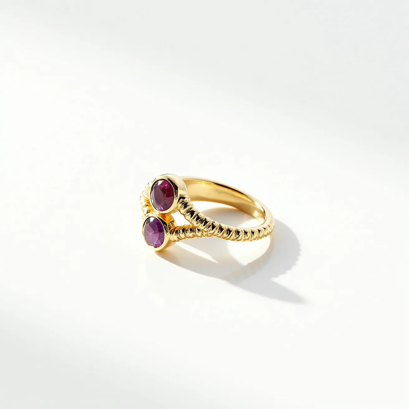 This wrap ring features a twisted gold band that elegantly coils around the finger. It is adorned with two oval-cut gemstones, likely rubies or garnets, each securely set in a smooth bezel setting. The rich red hue of the stones contrasts beautifully with the warm gold, amplifying its regal aesthetic. The ring does not include any clasps or additional attachments, as it relies on its wrap design to sit comfortably and securely on the wearer's finger.