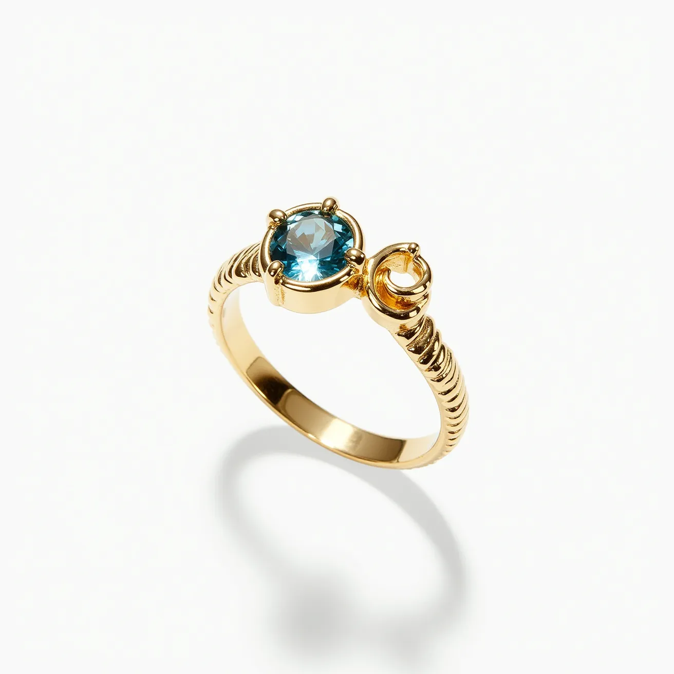 This wrap ring features a sleek gold band with a distinctive coiled design that elegantly wraps around the finger. It is adorned with a brilliant blue gemstone, possibly a topaz, cut in a round shape and set in a secure prong setting. Accompanying this central gem is a smaller, circular gold element that adds artistic flair to the overall design. The craftsmanship emphasizes both elegance and a modern aesthetic, making it a unique piece of jewelry.