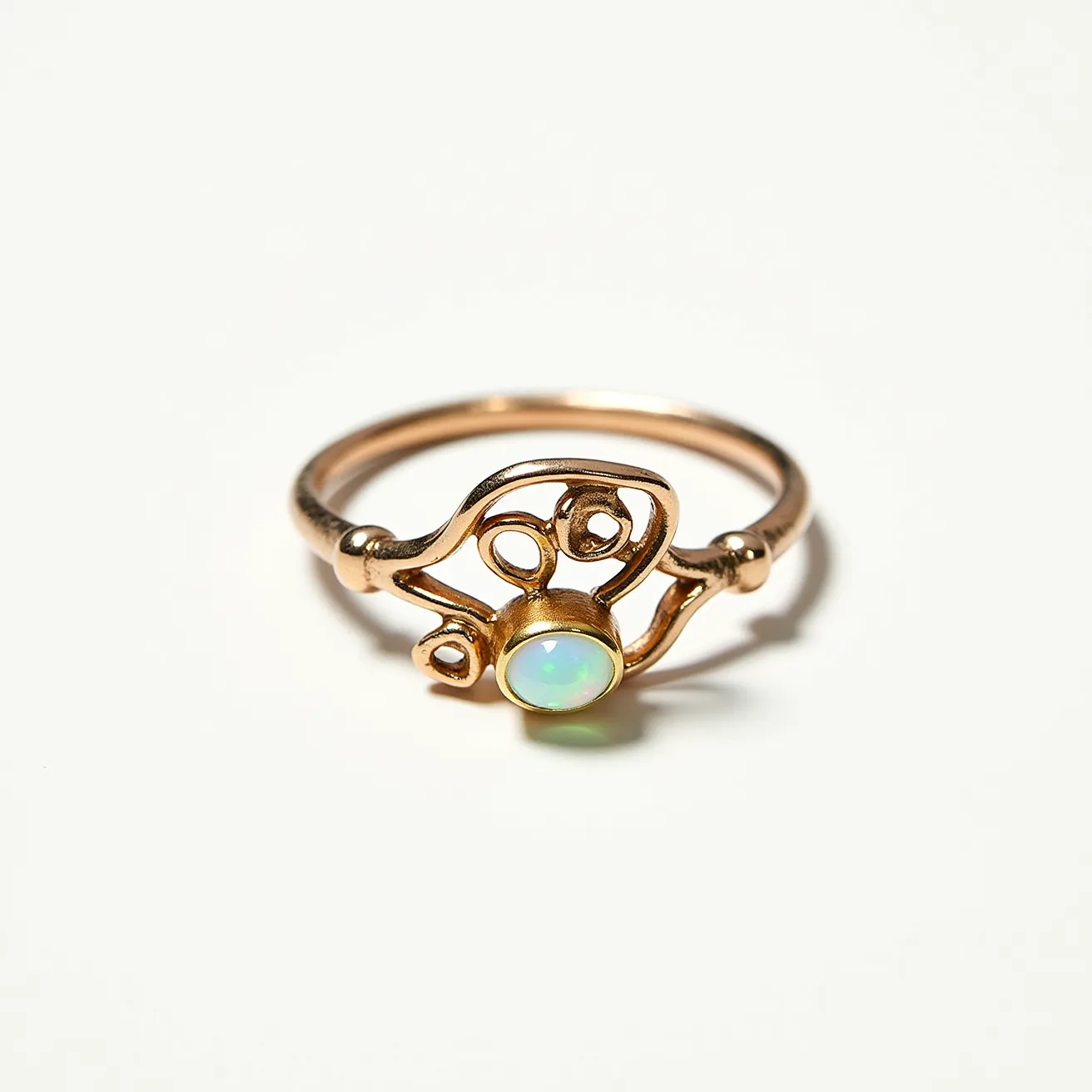 This wrap ring showcases a delicate design crafted from gold, featuring an intricately formed band that twists into artistic loops. At its center, the ring is adorned with a round opal gemstone, noted for its iridescent play of colors, securely held in a bezel setting. The opal's setting is smoothly integrated into the flowing design of the band, allowing the gem to be the focal point without additional clasps or attachments, emphasizing the ring's elegant and seamless style.