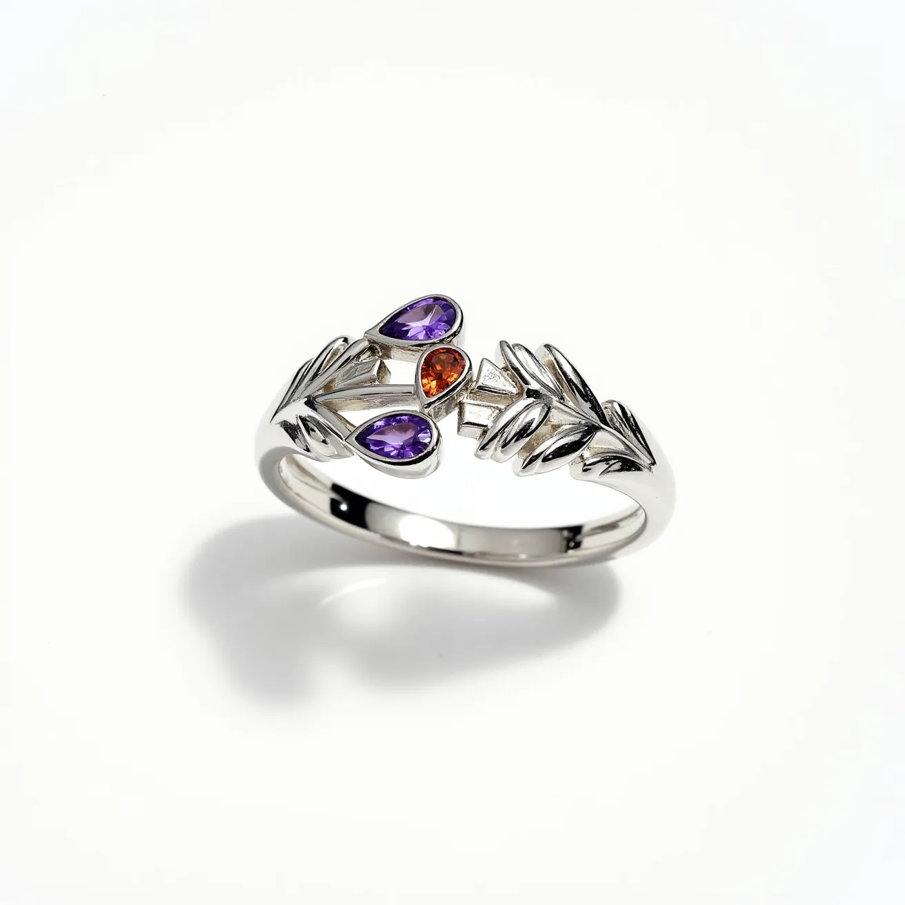 This wrap ring features an elegant design crafted from polished silver, adorned with three gemstones. It showcases two purple pear-shaped stones, possibly amethysts, set on either side, enhancing its symmetrical allure. In the center is a round, brilliant-cut orange stone, which could be a citrine or garnet, adding a vibrant contrast. The stones are securely set in a bezel style, integrating seamlessly into the ring’s design. The open-ended wrap style finished with leafy motifs completes the sophisticated look, offering a contemporary yet timeless appeal.