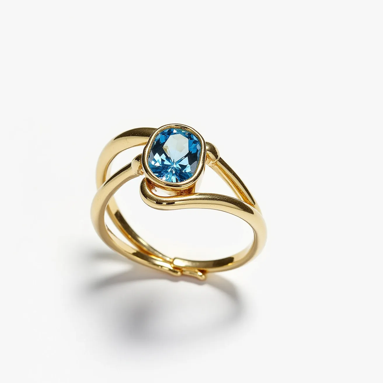 This wrap ring features a sleek, open design crafted from a polished gold metal, exuding a sophisticated allure. It showcases a prominent blue gemstone, which appears to be an oval-cut, securely set in a bezel setting. The vibrant blue stone is highlighted beautifully by the gleaming gold, adding a touch of elegance and color contrast. The wrap style provides a contemporary feel, making the ring both a statement piece and versatile accessory, seamlessly blending boldness with classic design elements.