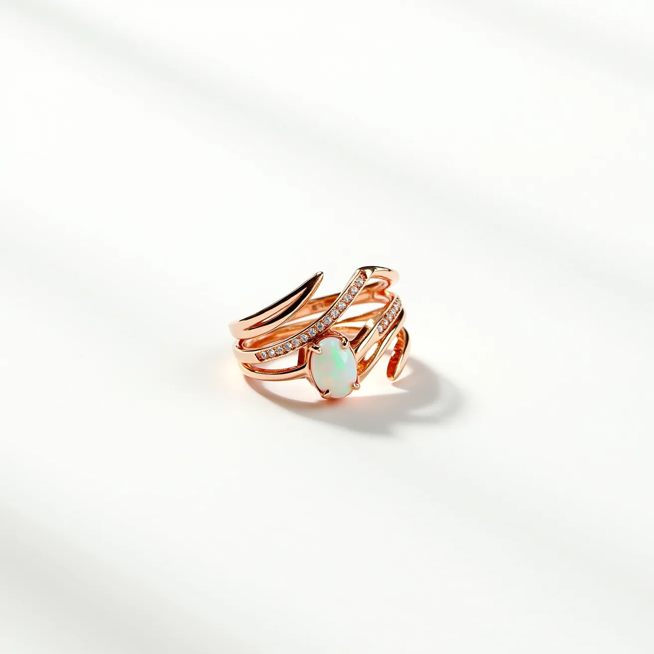 This wrap ring is made of rose gold with an elegant layered design that envelops the finger in a fluid motion. It features a central opal stone, cut in an oval shape, held securely in a prong setting. The band is embellished with small, round-cut white stones, likely diamonds or cubic zirconia, arranged in a pave setting, adding a touch of sparkle. The open-ended design provides a unique twist, allowing the ring to maintain a seamless and adjustable fit without the need for a clasp or traditional closure.